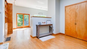 Una habitación amplia con suelo de madera, un gran ventanal corredero que da a un balcón y un armario de madera.