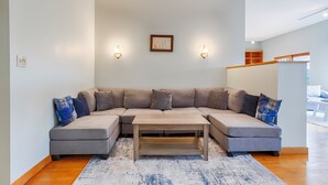 Una sala de estar moderna con un sofá seccional, una mesa de centro de madera y dos lámparas fijadas a la pared.