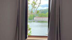 Una habitación con ventana que da a un río y un edificio al otro lado del agua.