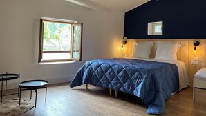 Un dormitorio con cama, ventana, mesita de noche y una pequeña mesa.