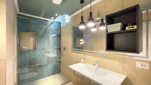 Un baño moderno con cabina de ducha de vidrio, un lavabo blanco y un espejo sobre el lavabo.