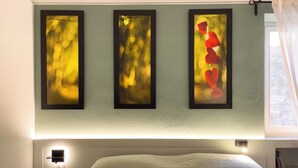 Un dormitorio con una cama, una mesita de noche y tres cuadros abstractos en la pared.