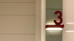 Una pared con un cartel con el número 3 y dos interruptores de luz.
