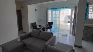 A living room with a sofa, a dining table with chairs, and a kitchen area visible through an open door. - Luxury Retreat Between City & Rodneybay-free Treat (Castries)