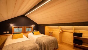Une chambre mansardée chaleureuse, avec deux lits, des murs en bois et un plafond en pente.