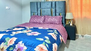 A bedroom with a bed, a nightstand, an air conditioning unit, and curtains. - ES Homes-2Bedroom Apartment at Achimota (Accra)