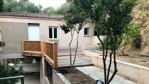 A residential property with a wooden deck, a small garden, and a house with a tiled roof.
