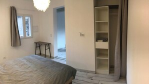 A bedroom with a bed, a chair, a wardrobe, and a small table.