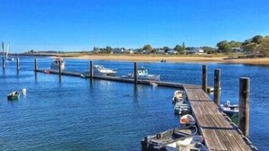 Un muelle de madera se extiende sobre una superficie acuática tranquila con varias embarcaciones amarradas.