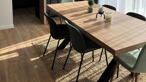 Uma cozinha moderna com uma bancada de mármore, uma mesa de jantar de madeira com cadeiras e uma luminária pendente.