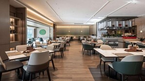 Een modern restaurant met een lange balie, meerdere tafels en een bar.
