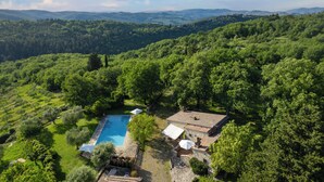 A villa with a swimming pool surrounded by lush greenery and hills in the background. - A Casa Dell'ida (Castellina in Chianti)