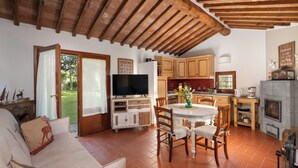 A cozy living room with a sofa, a dining table with chairs, a television, wooden cabinets, and a fireplace. - A Casa Dell'ida (Castellina in Chianti)