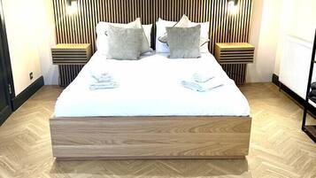 Ein modernes Hotelzimmer mit einem großen Bett, einem Holz-Kopfende und einem Fischgrätparkett.