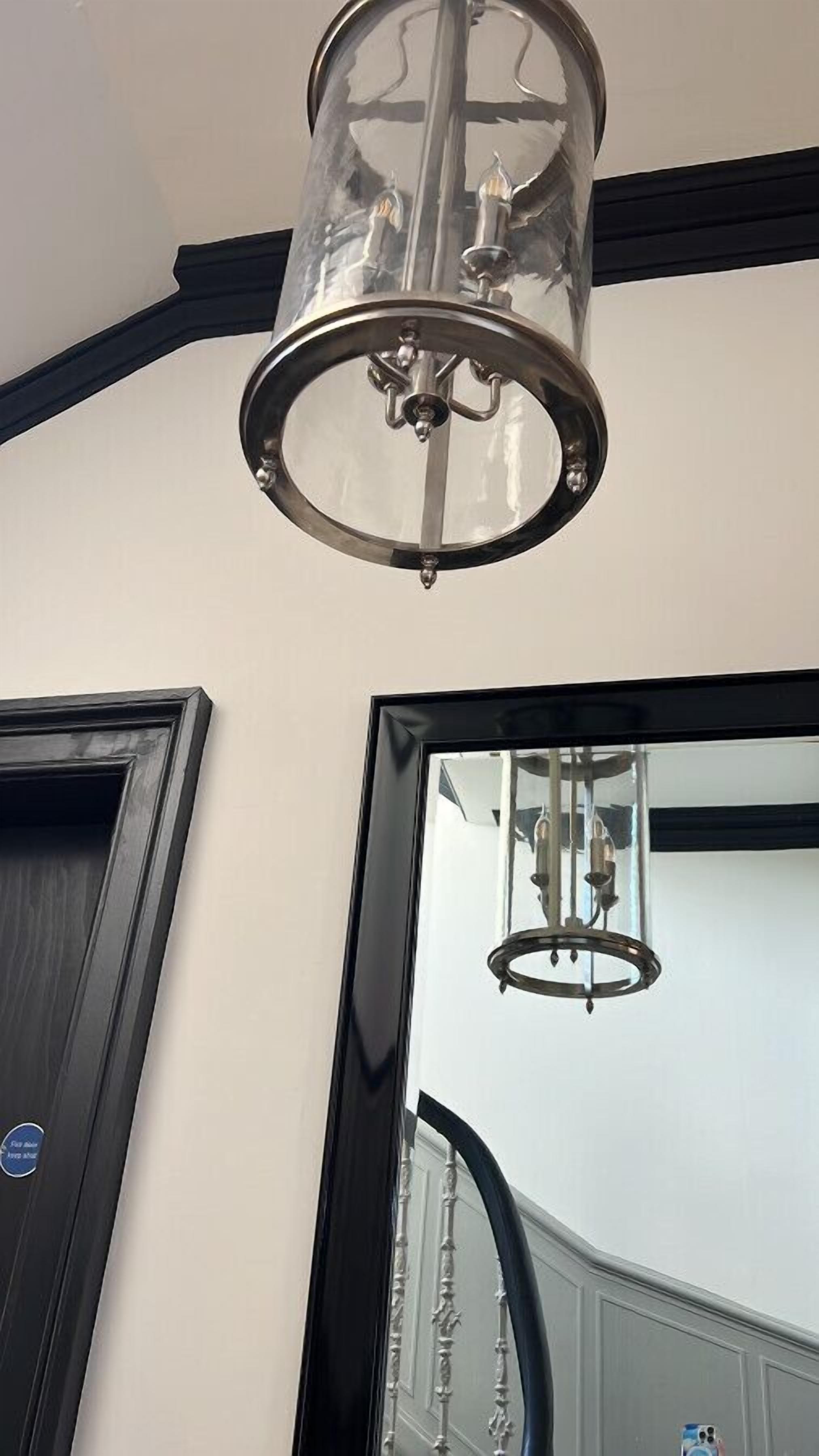 A modern interior with a large mirror, a chandelier, and a staircase.
