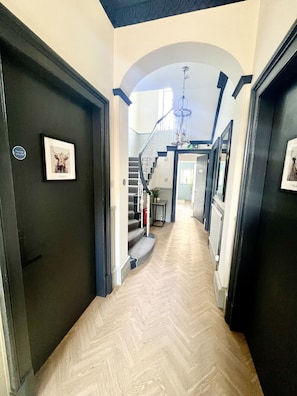 A hallway with a herringbone floor, a staircase, and a chandelier. - 'Mac' in Allandale ApartHotel (Auchterarder)