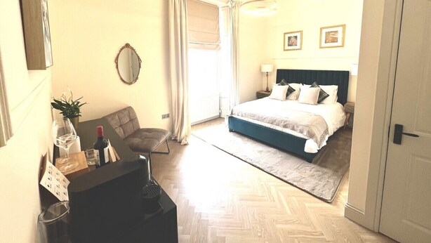 Ein Hotelzimmer mit Bett, Stuhl, Tisch und einer Weinflasche sowie einem Spiegel.