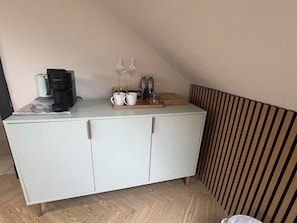 A kitchenette with a coffee maker, two wine glasses, and a tray with cups. - 'Fergus' in Allandale ApartHotel (Auchterarder)