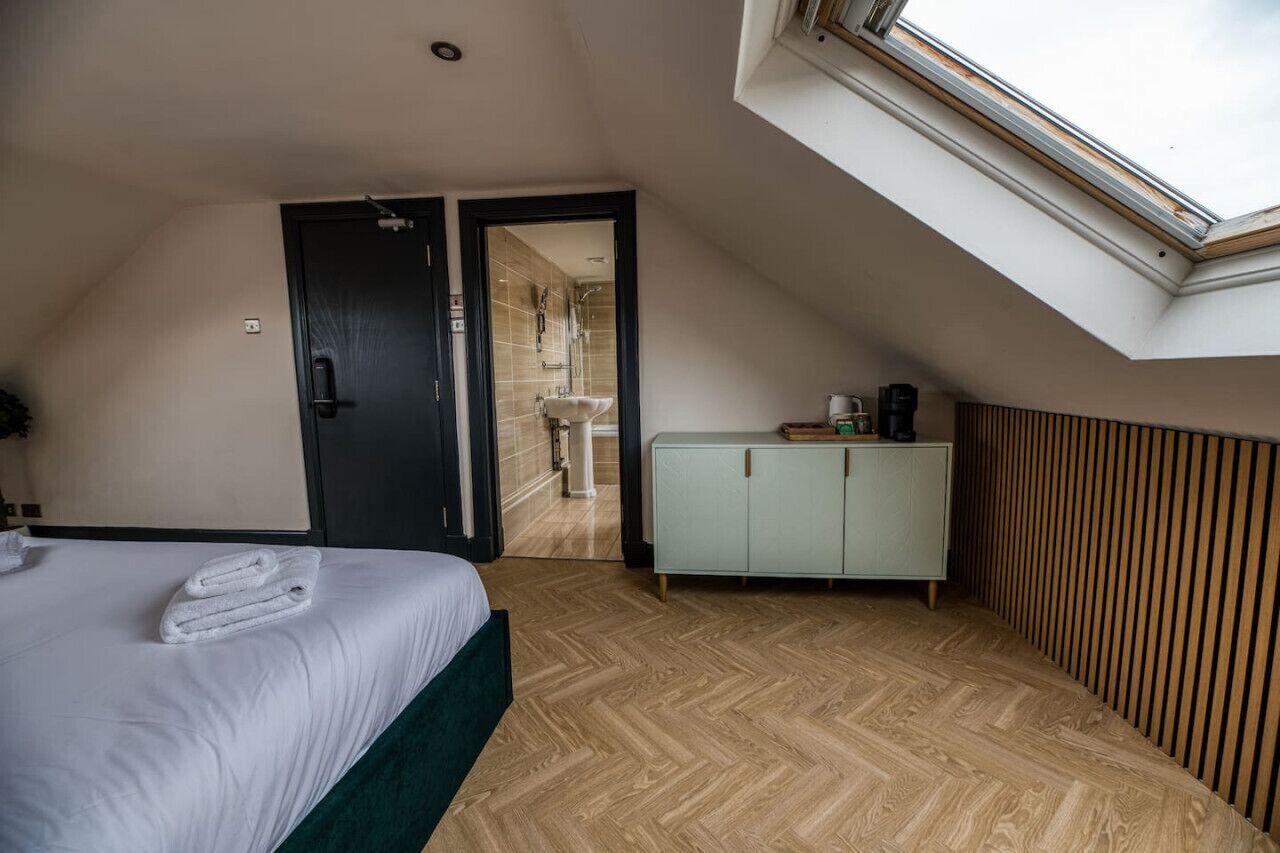 Ein Schlafzimmer mit Bett, Kleiderschrank, Badezimmer mit Dusche und einem Oberlicht.