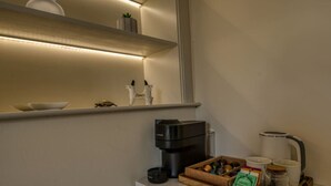 A kitchenette with a coffee maker, a kettle, and a tray with coffee pods and a jar of sugar.