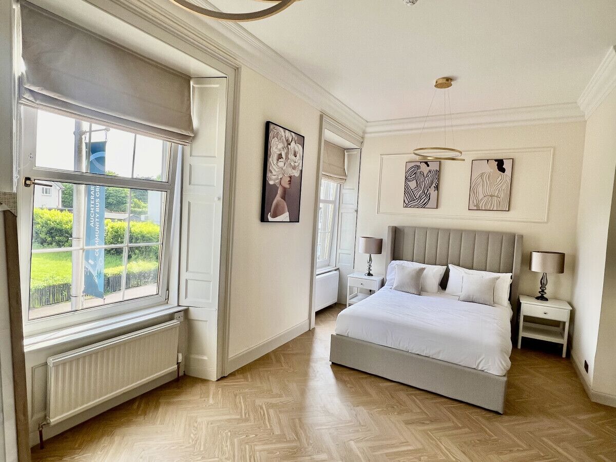 Een slaapkamer met een groot bed, een raam met uitzicht en een radiator.