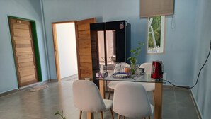 A modern dining area with a glass table, two chairs, a coffee machine, and a plant. - IRUKA GUESTHOUSE (Fiyoaree)