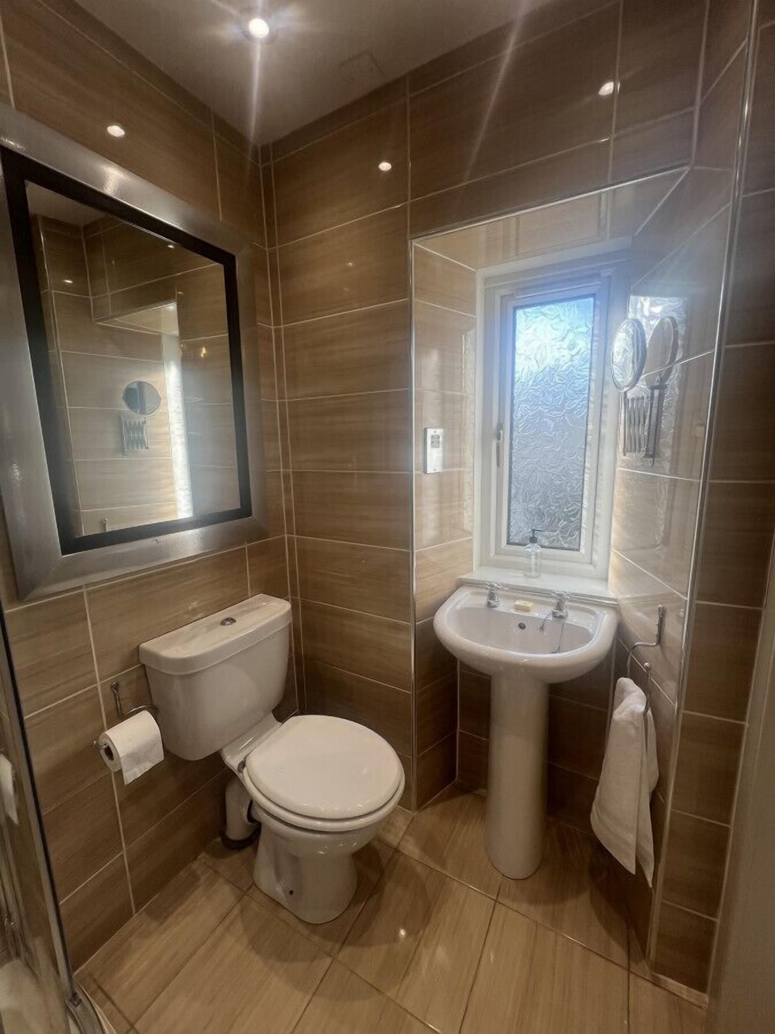 A compact bathroom with a toilet, sink, and mirror.