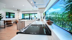 A modern kitchen with a large island, built-in appliances, and a view of greenery through large windows. - NEW 4 bd 3 bth, heated pool, golf cart block from beach (Indian Rocks Beach)