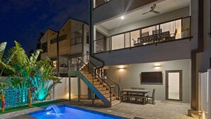 A two-story house with a swimming pool, outdoor furniture, and a staircase leading to the upper floor. - NEW 4 bd 3 bth, heated pool, golf cart block from beach (Indian Rocks Beach)