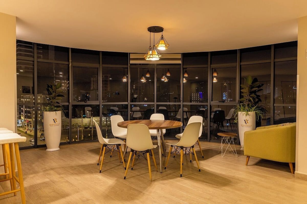 A modern dining area with a round table, white chairs, and pendant lighting.