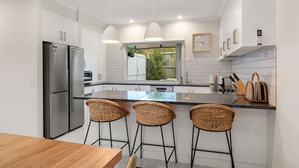 A modern kitchen with stainless steel appliances, a large island with bar stools, and a window providing a view of the outdoors.