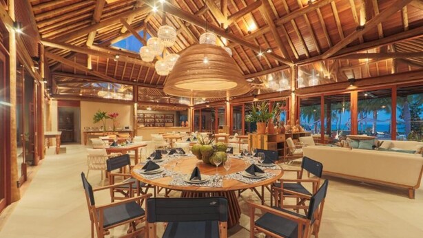 A spacious dining area with a wooden table set for a meal, surrounded by chairs. - Anttunina Pousada E SPA (106189278) (Maragogi)