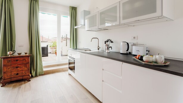 A modern kitchen with white cabinets, a black countertop, and a view to the outside. - Amazing flat with big terrace and private car park (Verona)