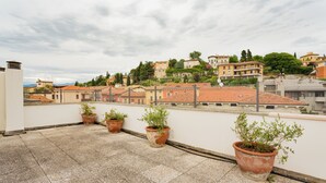 A rooftop terrace with potted plants and a view of a town with terracotta-roofed buildings. - Amazing flat with big terrace and private car park (Verona)