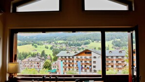 Ein großes Fenster mit Blick auf ein Bergdorf und ein Hotel mit Balkonen.