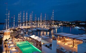 A marina at dusk with multiple sailboats docked, a swimming pool, and outdoor seating areas. - NEW! Villa Roberta - walk distance to Porto Cervo (Porto Cervo)