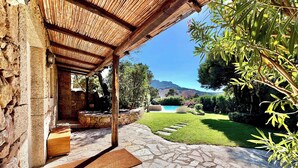 Une terrasse en pierre mène à un espace extérieur abrité, doté d’une piscine et offrant une vue sur les montagnes.