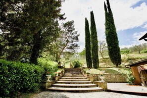 A stone staircase leading up to a building with a wooden barrel and a stone wall.