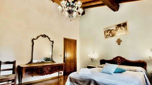 A bedroom with a wooden bed, a wooden desk with a mirror, a wooden chair, a wooden wardrobe, and a chandelier. - Beautiful country house in the heart of Tuscany (Capolona)