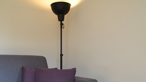 A modern living room with a grey sofa, a wooden coffee table, a book, a potted plant, and a floor lamp.
