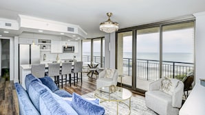 A spacious living area with a large sofa, a dining table, and a balcony with a view of the ocean. - Remodeled, Open Airy Condo, With Full Access , 1706 Brighton 3 Bedroom Condo (Myrtle Beach)