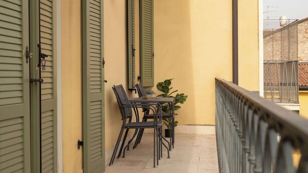 Ein Balkon mit Tisch, Stühlen, einem Blumentopf und einer Brüstung.