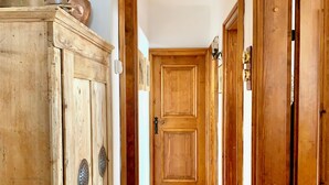 A wooden hallway with a wooden door at the end, a wooden cabinet with metal handles, and a metal pot on top. - Cozy flat with direct access to garden (Cortina d'Ampezzo)