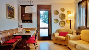 A cozy dining area with a wooden table and red chairs, a sofa, and a lamp. - Cozy flat with direct access to garden (Cortina d'Ampezzo)