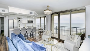 A spacious living area with a large sofa, a dining table, and a kitchen in the background. - Remodeled, open airy condo with full resort access, 1706 Brighton (Myrtle Beach)