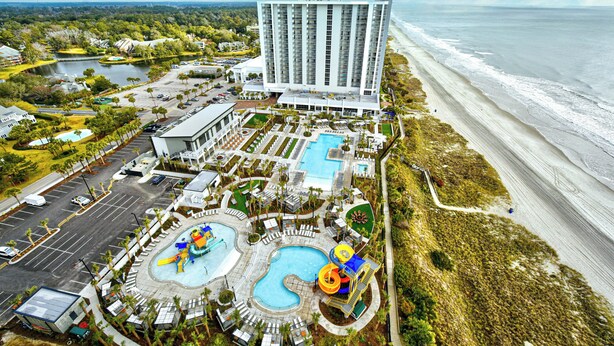 A resort with a large pool area, a water slide, and a beach view. - Remodeled, open airy condo with full resort access, 1706 Brighton (Myrtle Beach)