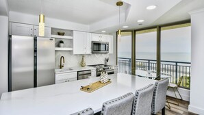 A modern kitchen with a large island, stainless steel appliances, and a view of the ocean. - Remodeled, open airy condo with full resort access, 1706 Brighton (Myrtle Beach)