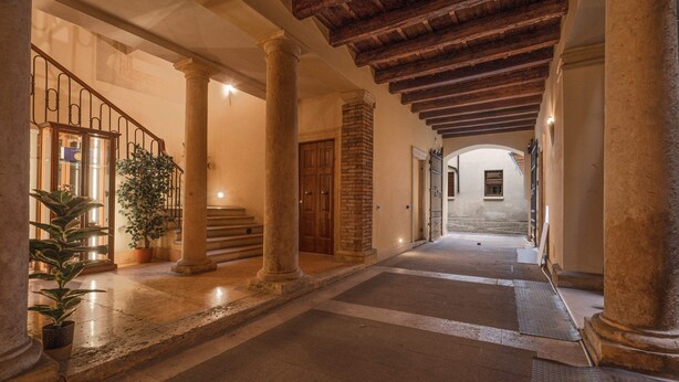 A corridor with columns, a staircase, and a wooden ceiling. - Palazzo Cavalli - Deco' (Verona)