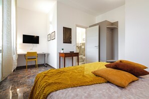 Une chambre d’hôtel comprenant un lit, un bureau, une chaise, une télévision et une salle de bain.
