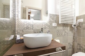 Une salle de bain avec un grand lavabo sur pied blanc, un miroir et des carreaux à motifs.